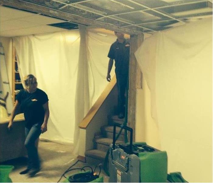 SERVPRO technicians working in a basement of a home setting up containment to help the drying process